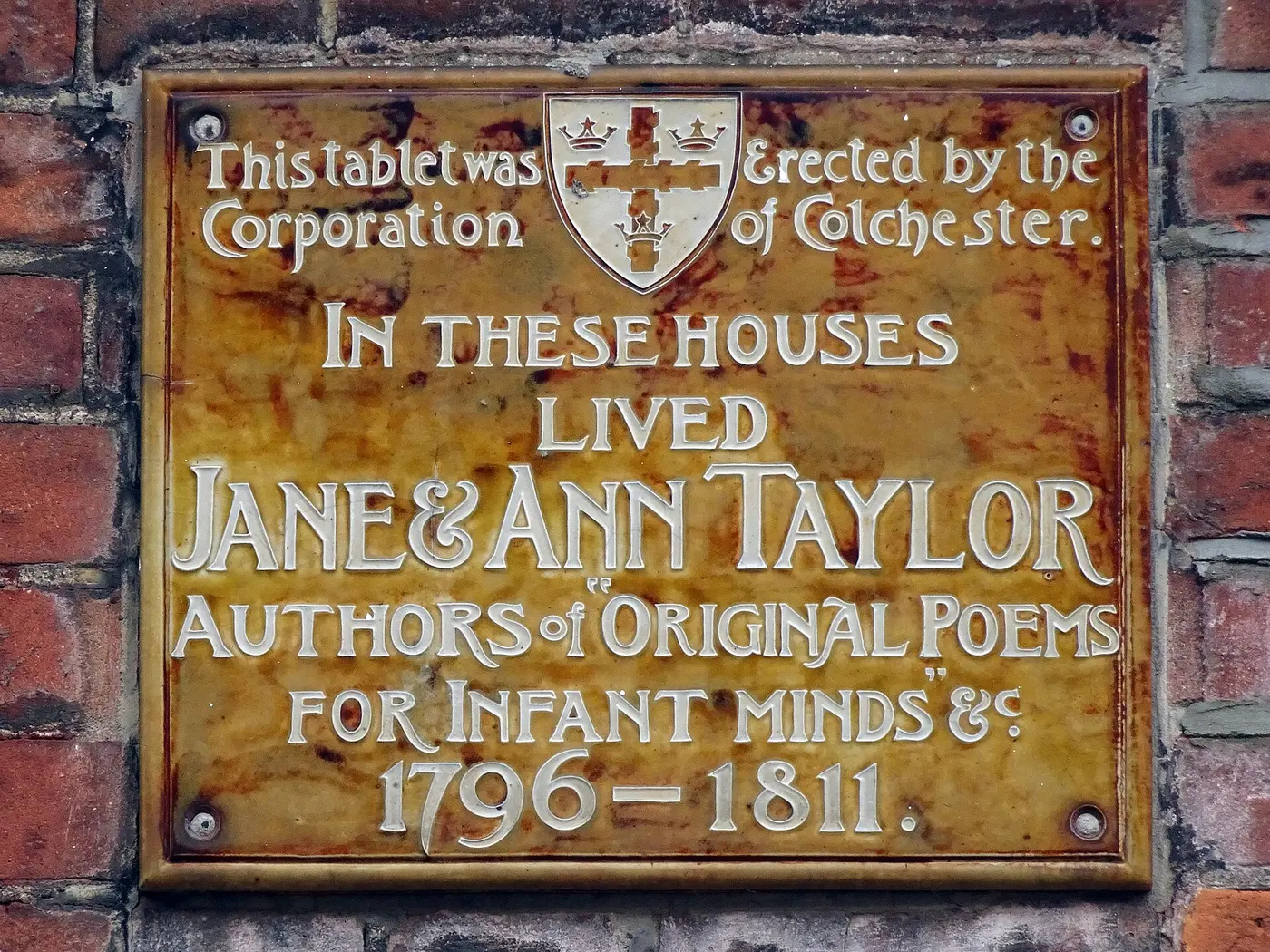 A brown plaque on a brick wall engraved with the names of Jane and Ann Taylor