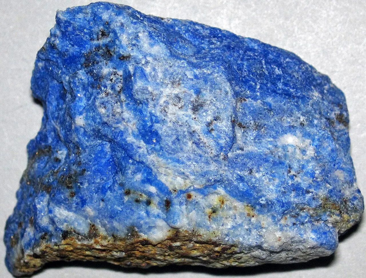 A rough chunk of stone, vivid blue with white streaks and tiny gold-colored specks
