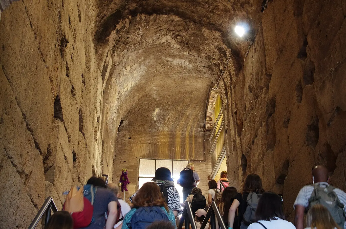 A staircase rising toward the seating under a vaulted stone ceiling in a passage of the Colosseum