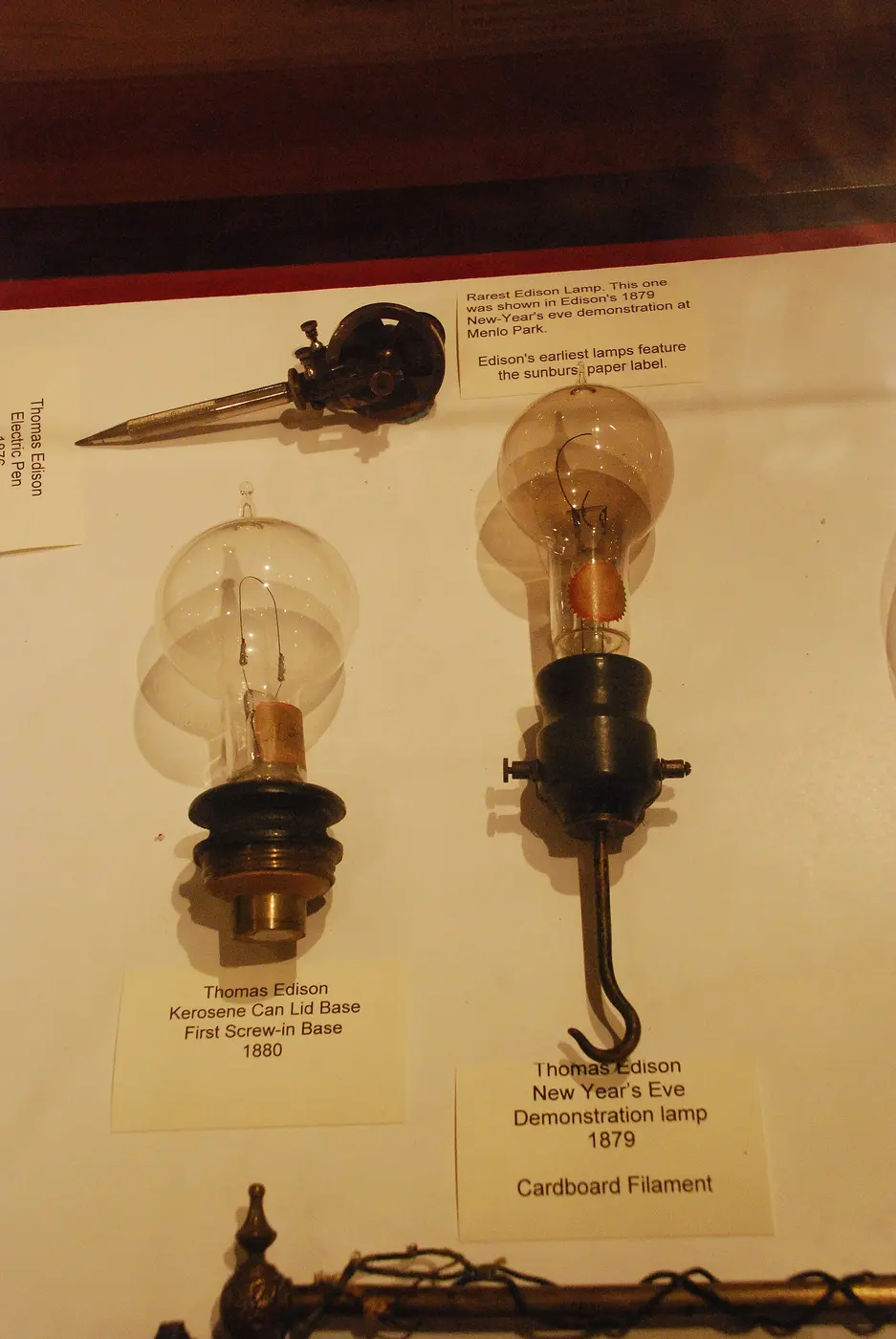 Two old light bulbs in a display case, each with a thin filament visible inside the glass