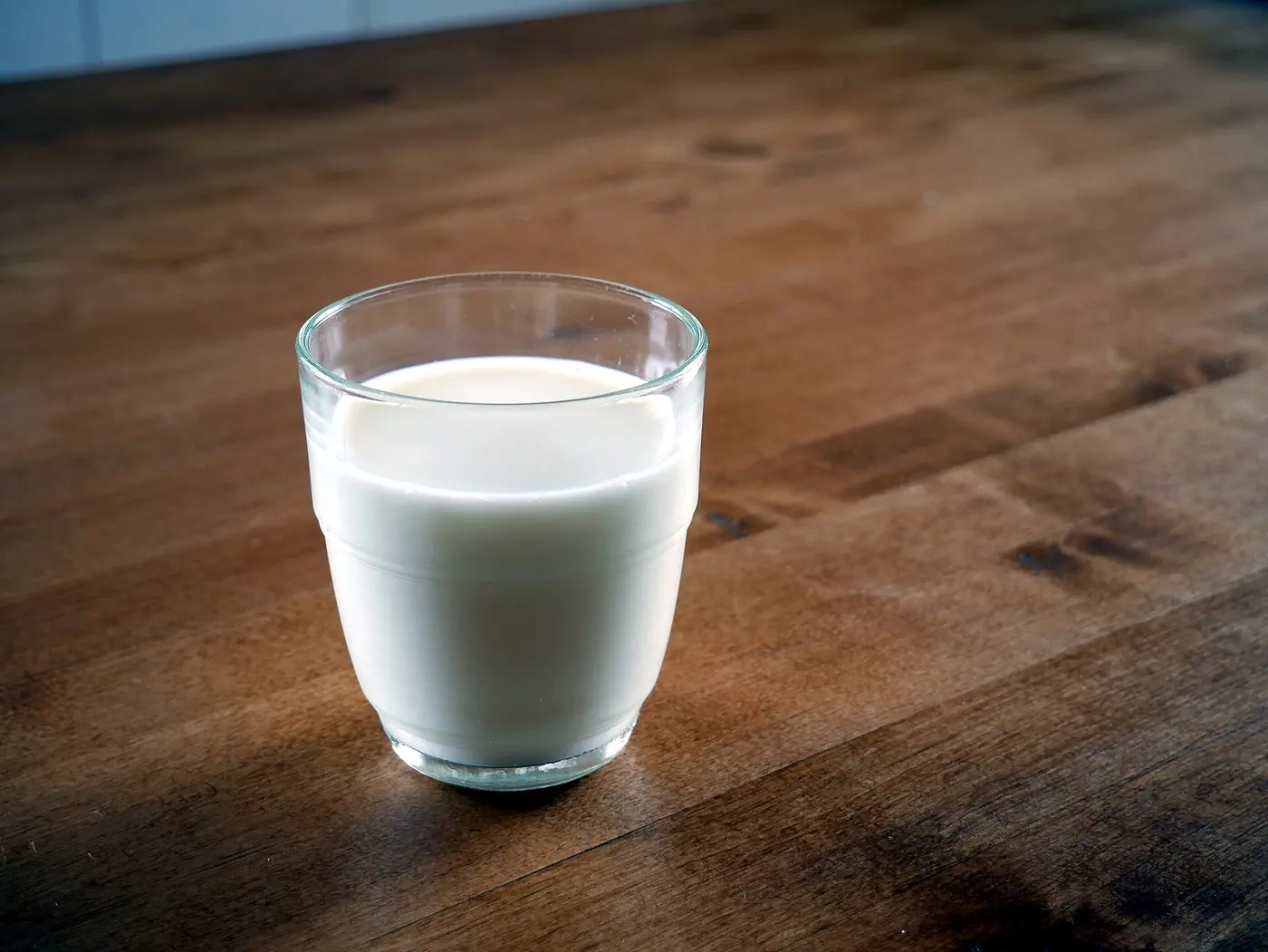 A clear glass of milk on a wooden table